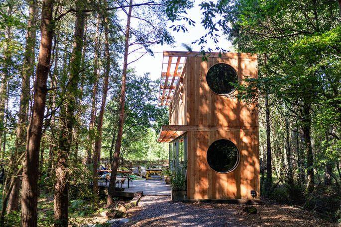 Two story cabin in woodland with porthole windows 