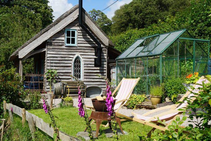 Exterior of large cabin with floxgloves, outdoor seating and greenhouse 