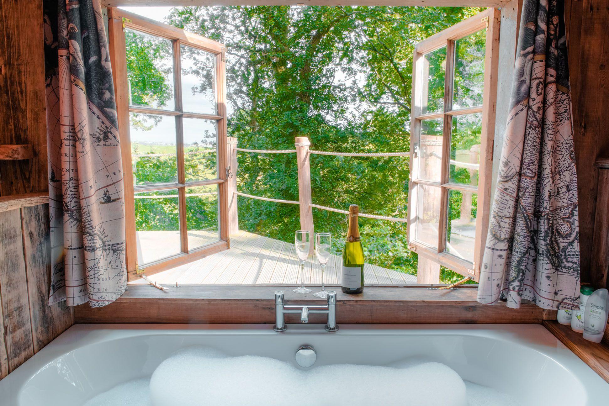 Bath and wine glasses looking out over a deck and trees