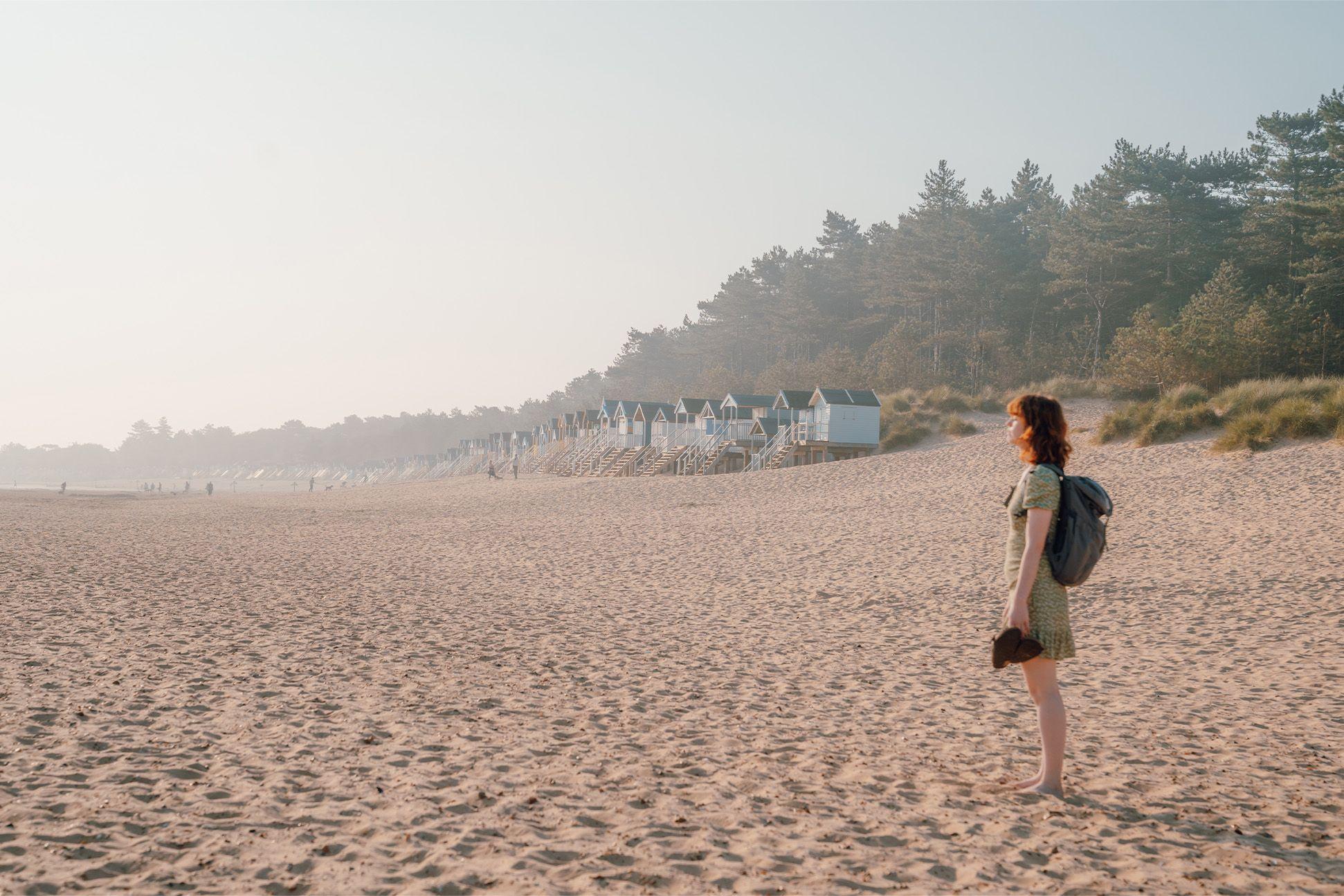 Woman on a beach holding her shoes