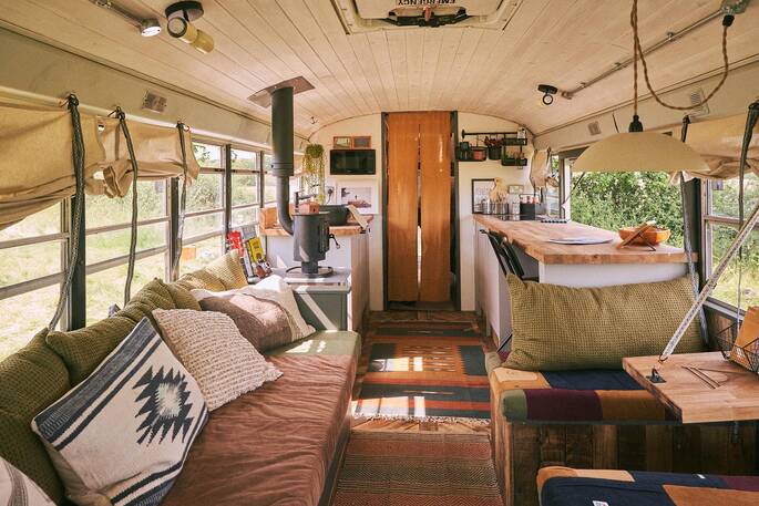 Interior with a wood burner, sofa, kitchen and dining area