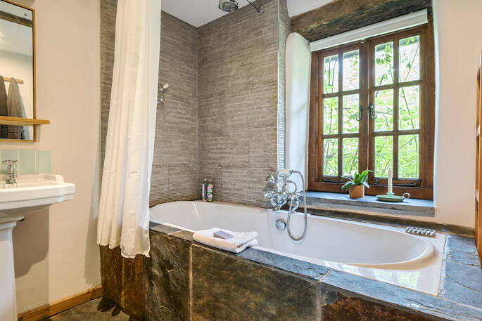 Great Burrow Cottage bathroom with a bath tub, sink and flushing toilet