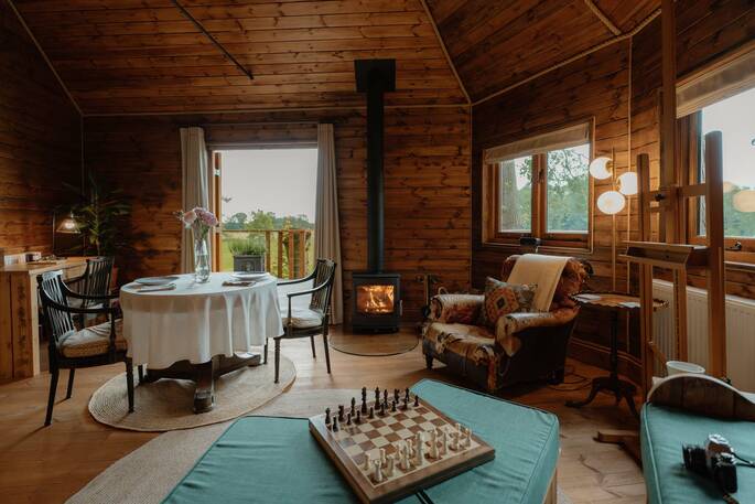 Open plan living area with sofas, a dining table and wood burner