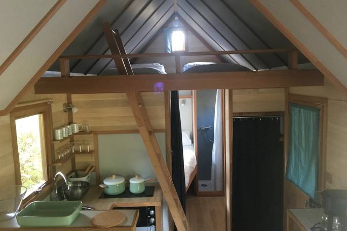 Inside of La Cabane de Bot-Conan with two single beds on mezzanine leave above the kitchen facilities